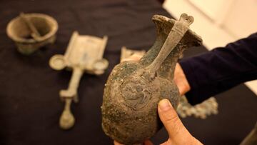 Uzi Rotstein, inspector in the The Prevention Unit at Israel Antiquities Authority, displays a bronze jug, one of a number of artifacts seized from antiquities dealers, bearing a depiction of a Roman banquet, consistng of a scene showing a reclining figure holding a jug of wine, at his office in the central city of Bet Shemesh on December 16, 2021. - The Israel Antiquities Authority believes that ancient artifacts seized from antiquities dealers were spoils taken in battle by Bar Kokhba rebels fighting Roman soldiers. Investigation into those involved in the case raises the suspicion that the finds were looted from a hiding complex in the Judean foothills that served as a refuge during the Bar Kokhba Revolt. They include two ornate 2,000-year-old bronze censers that were used to burn ritual incense and probably belonged to affluent Roman houses and temples. A bronze jug for serving wine was also recovered. The vessel bears a depiction of a Roman banqueting scene showing a reclining figure holding a jug of wine. Other illicit finds include an ornate stone tripod bowl, Roman clay lamps, and hundreds of coins dating from the Late Roman period (secondx96third centuries CE). (Photo by MENAHEM KAHANA / AFP)