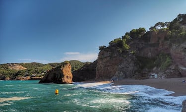 Recibe su nombre por la roca rojiza que le caracteriza. De ambiente tranquilo y rodeada de acantilados, ofrece aguas limpias y profundas, ideales para el baño y el snorkel. Su acceso a pie garantiza una experiencia más íntima, lejos del turismo masivo. Es también conocida por ser una playa naturista, respetuosa y discreta.