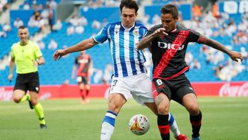 SAN SEBASTIÁN, 22/08/2021.- El centrocampista de la Real Sociedad Martín Zubimendi (i) pelea un balón con el centrocampista argentino del Rayo Vallecano Óscar Trejo durante el partido de LaLiga, este domingo en el Reale Arena.