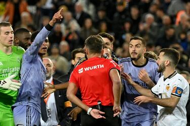 Los jugadores del Real Madrid protestan al árbitro del encuentro, Gil Manzano, tras la decisión de anular el gol a Jude Bellingham. En la imagen, el colegiado se lleva la  mano al bolsillo para sacar la tarjeta roja al jugador inglés.