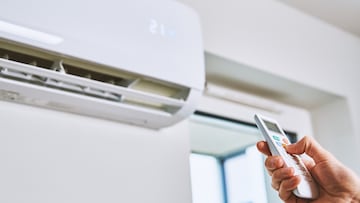 Hand adjusting temperature on air conditioner with remote control, Working air conditioner for comfort temperature in home at hot summer
