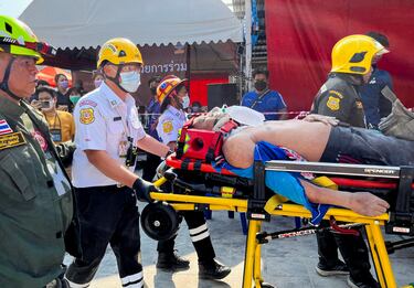Una persona herida es sacada en camilla por personal de emergencia cerca del lugar del derrumbe de un edificio.