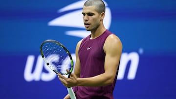 Carlos Alcaraz mira su raqueta durante su partido contra Reilly Opelka en el US Open.