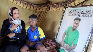Doaa, viuda de Suleiman Al-Obeid, junto a uno de sus hijos, con una imagen del futbolista palestino asesinado en Gaza.
