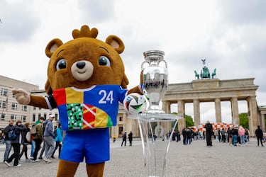 El osito Albärt, la mascota de la Eurocopa de Alemania 2024, posa ante el público con el balón oficial y el trofeo del torneo delante de la Puerta de Brandenburgo, en Berlín. El campeonato europeo de selecciones de fútbol tendrá lugar del 14 de junio al 14 de julio en diez estadios del país germano, incluido el Olímpico de Berlín. 