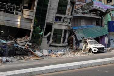 Un vehículo queda atrapado bajo los escombros de un edificio que se derrumbó tras un fuerte terremoto en Mandalay, Myanmar.