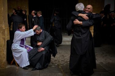 Un penitente de la hermandad de Los Estudiantes es bendecido tras confesarse con un sacerdote mientras se preparan para salir en procesión durante la Semana Santa en Sevilla.