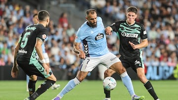 Borja Iglesias controla el balón ante la presencia de dos jugadores del Betis.