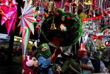 Las mujeres compran adornos navideños en un mercado al borde de la carretera en Ahmedabad, India.