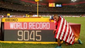 El estadounidense Ashton Eaton posa junto al marcador en el que se señala su récord mundial.