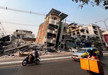 Los pasajeros pasan junto a un edificio que se derrumbó tras un fuerte terremoto en Mandalay, Myanmar.