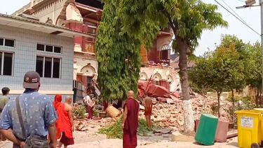 Personas cerca de un templo derrumbado tras un terremoto en Mandalay, Myanmar.