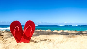 Red flip flops in heart shapes on the sandy beach in Hawaii, Kauai (romantic concept)