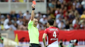 French refeere Ruddy Buquet (L) delivers a red card to Monaco's Spanish midfielder Cesc Fabregas during the French L1 football match between AS Monaco (ASM) and Olympique Lyonnais (OL) at the Stade Louis II stadium in Monaco on August 9, 2019. (Photo