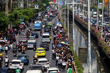 La gente se encuentra en la carretera mientras los autos avanzan a través del tráfico después de que un fuerte terremoto sacudiera el centro de Myanmar.