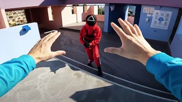 Una chica vestida con el traje rojo de Squid Game de Netflix, con una arma y un triángulo en la cabeza, amenaza a un freerunner que levanta las manos para que no le dispare.