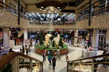 La gente camina en el centro comercial SOCOCE (HYPER U) decorado con iluminación antes de la celebración navideña en Abidjan, Costa de Marfil. 