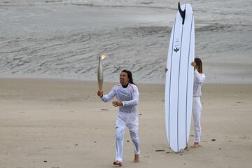 El surfista francés Edouard Delpero (izquierda) corre con la llama olímpica flanqueado por la surfista Zoe Grospiron (derecha).