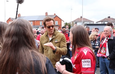 El actor y copropietario del Wrexham, Ryan Reynolds, habla con los aficionados fuera del estadio antes del partido.