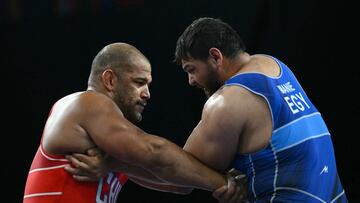Chile's Yasmani Acosta Fernandez (red) wrestles Egypt's Abdellatif Mohamed (blue) during their men's greco-roman 130kg wrestling quarter-final match at the Champ-de-Mars Arena during the Paris 2024 Olympic Games, in Paris on August 5, 2024. (Photo by Luis ROBAYO / AFP)