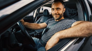 Confident man smiling and looking relaxed while sitting in a car with a seat belt fastened