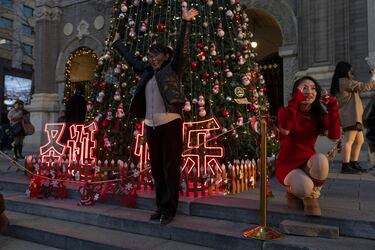 Las mujeres posan para las fotografías cerca de las palabras "Feliz Navidad" en vísperas de Navidad frente a una iglesia en Beijing. 
