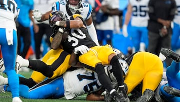 Aug 21, 2025; Charlotte, North Carolina, USA; Pittsburgh Steelers running back Jaylen Warren (30) stretches back for the yard marker tackled by Carolina Panthers defensive end Jared Harrison-Hunte (75) during the first quarter at Bank of America Stadium. Mandatory Credit: Jim Dedmon-Imagn Images