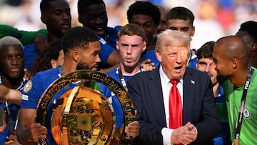 EAST RUTHERFORD, NEW JERSEY - JULY 13: Reece James #24 of Chelsea FC holds the FIFA Club World Cup trophy after their team's victory as U.S. President Donald Trump interacts with Robert Sanchez #1 of Chelsea FC following the FIFA Club World Cup 2025 Final match between Chelsea FC and Paris Saint-Germain at MetLife Stadium on July 13, 2025 in East Rutherford, New Jersey. David Ramos/Getty Images/AFP (Photo by David Ramos / GETTY IMAGES NORTH AMERICA / Getty Images via AFP)