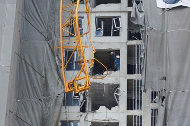 Vista de una grúa dañada, mientras trabajadores de la construcción inspeccionan los daños en un edificio en construcción, luego de un fuerte terremoto, en Bangkok, Tailandia.