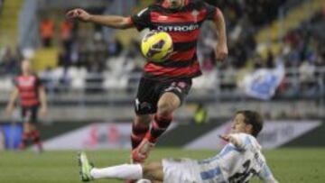 El defensa del Celta, Jonathan Castro "Jonny" (arriba), supera al centrocampista argentino del Málaga CF, Diego Buonanotte, durante el partido, correspondiente a la vigésima jornada de la Liga en Primera División, que ambos equipos disputan esta noche en el estadio de la Rosaleda, en Málaga.