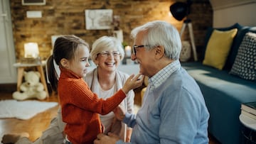 Happy senior couple enjoying with their granddaughter at home.