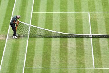 Un operario coloca un poste de la red antes de la final masculina del torneo de Wimbledon.
