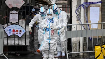 Health workers in protective gear walk out from a blocked off area after spraying disinfectant in Shanghai's Huangpu district on January 27, 2021, after residents were evacuated following the detection of a few cases of COVID-19 coronavirus in the neighbourhood. (Photo by STR / AFP) / China OUT