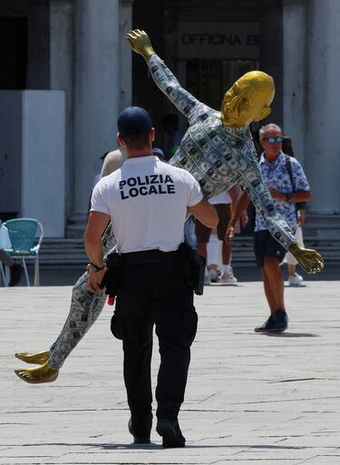 Un policía se lleva un maniquí que representa al fundador de Amazon, Jeff Bezos, cubierto de billetes falsos.