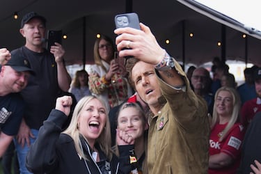 El copropietario del Wrexham, Ryan Reynolds (derecha), se toma una selfie con los aficionados en el estadio Racecourse antes del partido.
