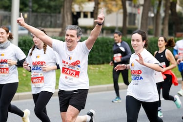 Participantes de la carrera "Madrid corre por Valencia" saludan durante el recorrido de la misma.