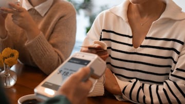 Dos mujeres pagando la cuenta en un restaurante.