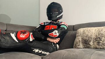 Fabio Quartararo sentado en su sofá vestido de piloto, con casco incluido.