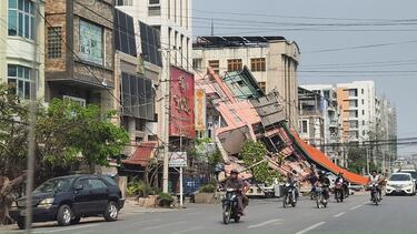 Personas en motocicletas pasan junto a un edificio dañado después de que un fuerte terremoto azotara el centro de Myanmar.
