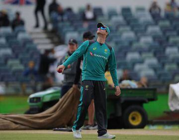 Australia's captain Steve Smith (C) looks to the sky as groundstaff prepare to cover the wet playing pitch during another rain delay prior to the start on day five of the third Ashes cricket Test match between England and Australia