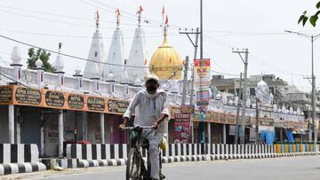 A man rides a bicycle along a street past closed shops following strict lockdown norms for weekends and public holidays imposed as a preventive measure against the COVID-19 coronavirus, in Amritsar on June 20, 2020. (Photo by NARINDER NANU / AFP)