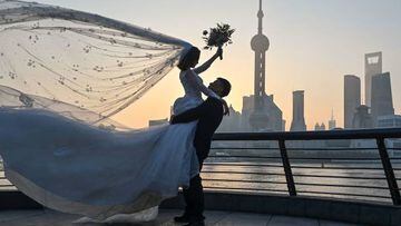 A couple poses for a wedding photo shoot on the Bund promenade along the Huangpu River during sunrise in Shanghai on September 7, 2022. (Photo by HECTOR RETAMAL / AFP) (Photo by HECTOR RETAMAL/AFP via Getty Images)