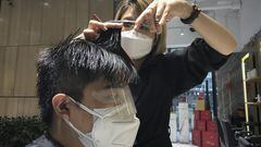 A barber wearing a protective face mask cuts a clients hair with an eye cover and face mask at a hair salon in Beijing, Monday, Feb. 24, 2020. Monday is the second day of the second month of the Chinese lunar calendar, traditionally an auspicious time when people rush into barbershops to get new haircuts. Getting a fresh look on the day is thought to bring good luck for the year ahead, but getting a haircut has become a challenge in China now that most barbershops are temporarily shut to avoid public gatherings amid the virus outbreak. (AP Photo/Olivia Zhang)