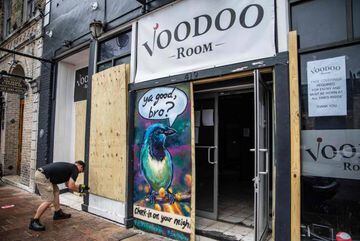 A worker drills a piece of plywood onto the facade of the Voodoo Room bar in Austin, Texas, June 26, 2020. - Texas Governor Greg Abbott ordered bars to be closed by noon on June 26 and for restaurants to be reduced to 50% occupancy. Coronavirus cases in T