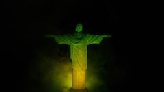 La estatua del Cristo Redentor en la montaña del Corcovado en Rio iluminado con los colores de la bandera de Brasil.