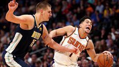 Devin Booker, #1 of the Phoenix Suns, drives to the basket against Nikola Jokic #15