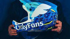 Las manos del piloto escoc&eacute;s de Mountain Bike Lewis Buchanan sujetan un casco de MTB customizado con los colores y el logo de OnlyFans. 