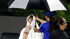 La tenista Aryna Sabalenka se cubre de la lluvia con una toalla durante su partido ante Elena Rybakina en las WTA Finals de Cancún.