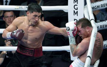 Dmitry Bivol (L) throws a left at Canelo Alvarez in the fifth round of their WBA light heavyweight title