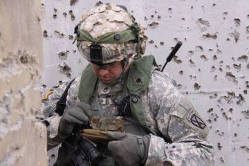 Un soldado consultando su smartphone en una zona en guerra